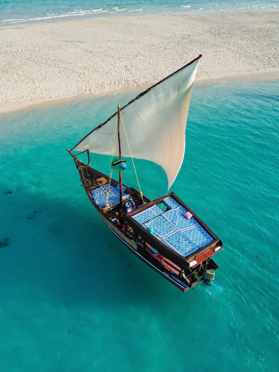 A traditional Zanzibar dhow sailing beside a white-sand island