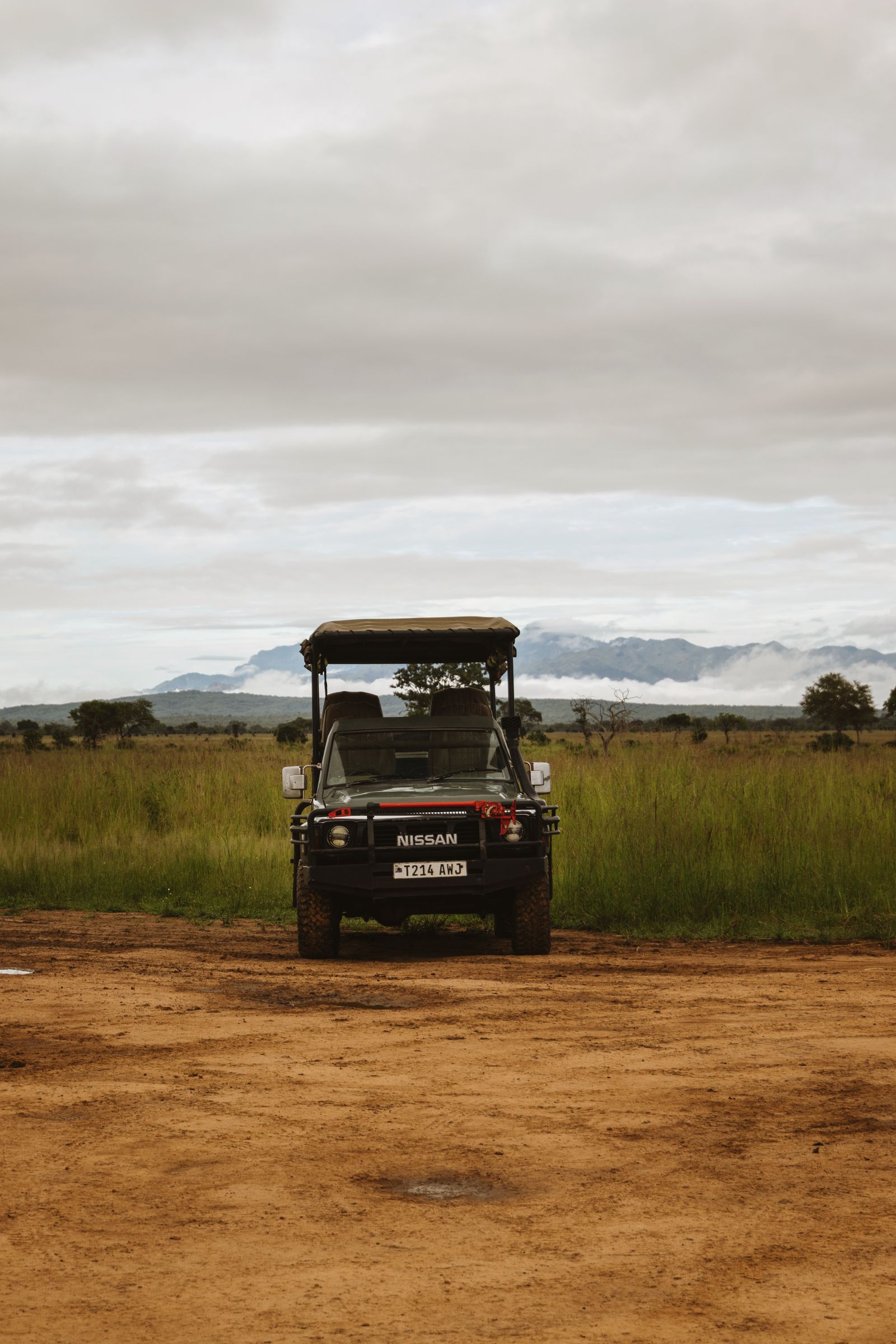 A safari vehicle on a dirt track across open grassland