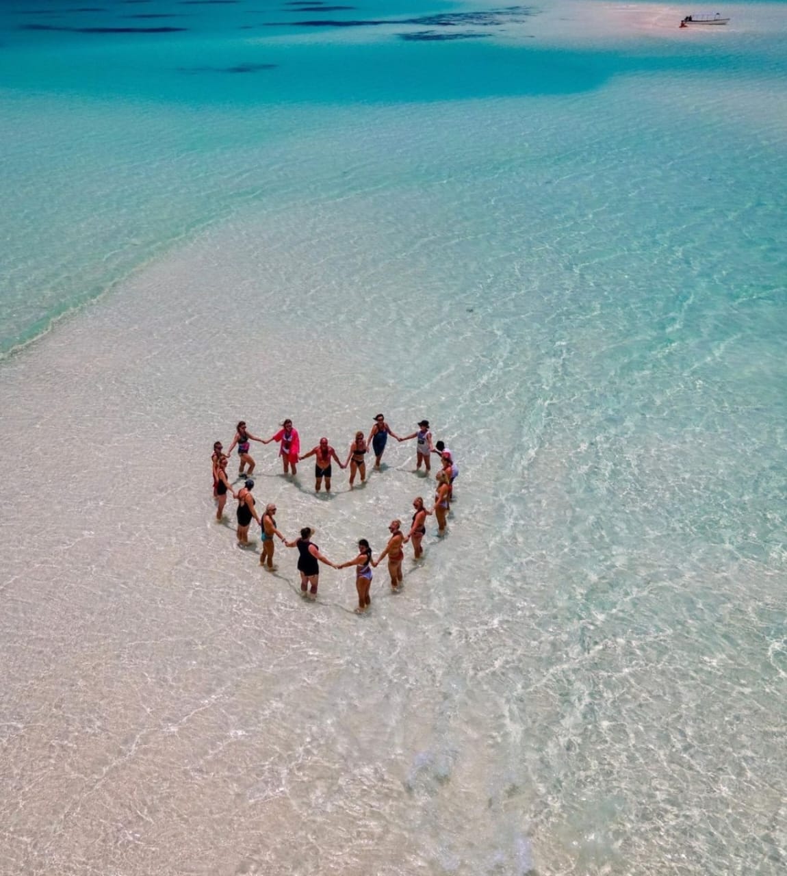 Travelers gathered in a circle on a shallow turquoise Zanzibar sandbank